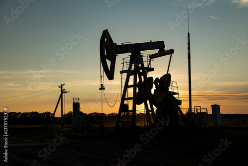 Drilling rig for extraction of fossil fuels and crude oil on the desert silhouette.