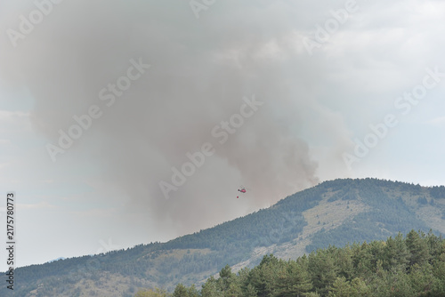 Konstfotografi Firefighting helicopter suppressing a forest fire on the mountain top