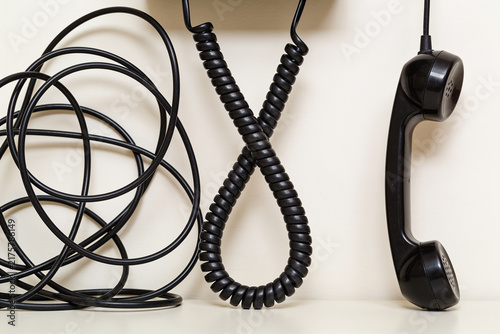 A badly tangled telephone cord beside the same cord hanging neatly