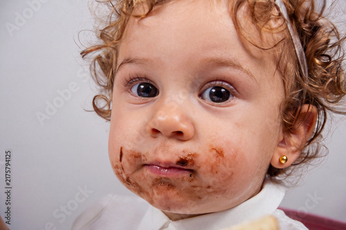 Portrait of a cute toddler girl with a messy chocolate face.