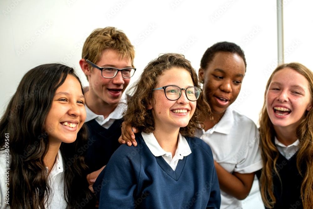 Fototapeta premium Group of diverse students laughing together in school uniforms.