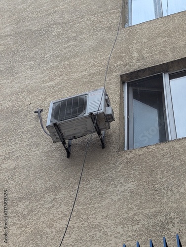 фотографія An old air conditioning unit mounted on an exterior wall beside a window