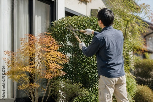 住宅の植木を整えて見通しを確保する人物