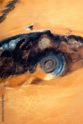 Eye of the Sahara, or Richat Structure, surrounded by golden desert sands in Mauritania, revealing its remarkable concentric geological rings from above.