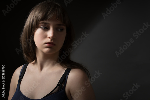 Portrait of a beautiful teenage girl posing against a dark background in beauty style