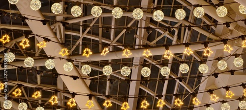 Foto Rows of glowing star‑shaped and crystal‑textured spherical bulbs suspended from metal beam ceiling