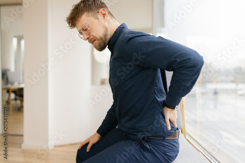 Businessman sitting in the office holding his back in pain