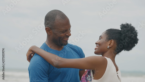 Bild auf Leinwand A Black couple shares a warm, emotional embrace on a beach