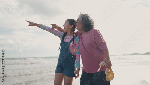Fotografie An Asian grandmother and her young granddaughter stand together on the beach, sm