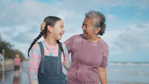 Foto An Asian grandmother affectionately pats her young granddaughter's head while wa