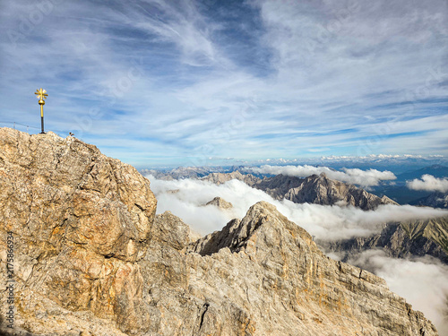 A high-angle, wide shot capturing the rugged, rocky summit of the Zugspitze mountain in the Alps.