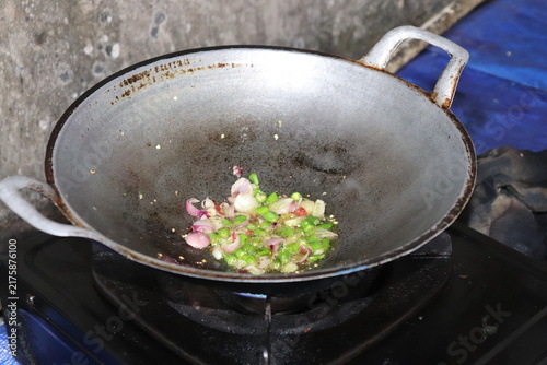 Foto Sauteing chopped shallots and green chilies in hot oil using a traditional metal