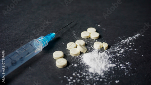 фотографія Misused concept of drugs, a syringe with some white drugs in powder and pill form