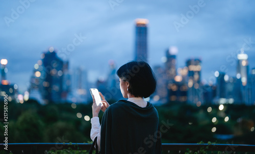 Business asian woman relax using smartphone social network communication metropolis city building background