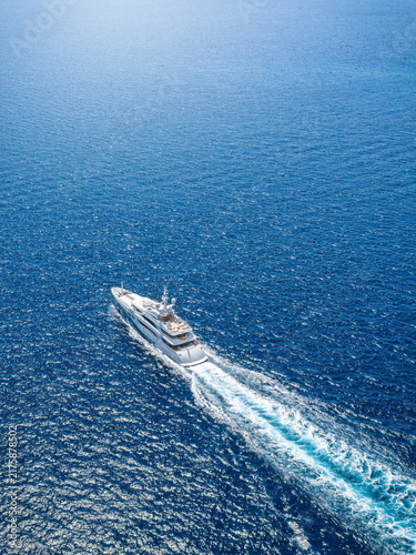 Aerial view of an ultra modern luxury yacht cruising over sparkling ocean with speed