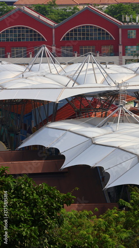 Bild auf Leinwand White tensile canopies layer beneath red riverside buildings in Singapore