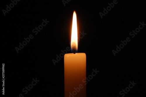 Принти на полотні Close-up of a burning candle with a bright glowing flame reflected in a dark surface, isolated against a black background