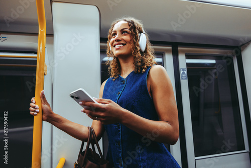 Happy woman checks smartphone while commuting on subway