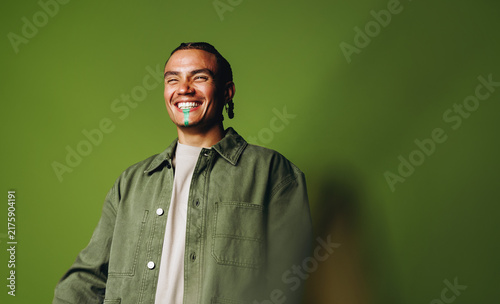 Portrait of a smiling man in green jacket smiling in studio against a green background