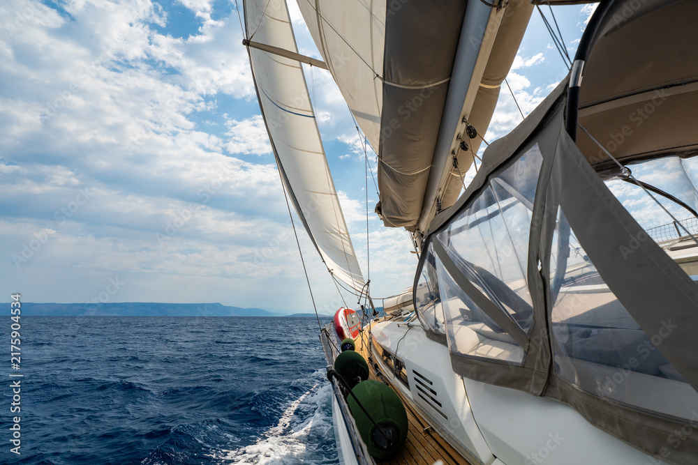 Fototapeta premium Dynamic view from deck of sailing yacht heeling under wind power while cutting through Adriatic waters. White wake, filled sails, a sense of speed, freedom and offshore adventure