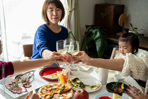 Smiling Asian Friends Toasting with Wine Glasses around Home Party Dining Table