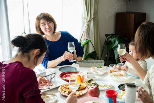 Asian Friends and Toddler Enjoying Home Party Conversation around Dining Table