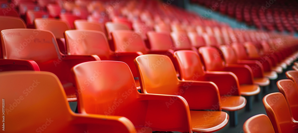 Obraz premium Rows of empty bright red stadium seats in an outdoor sports arena ready for a game, concert, or public event with perspective depth, vibrant orange tones, and clean modern architecture design aestheti