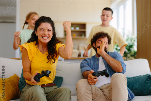 Photography Happy family enjoying a competitive game at home, with the mother cheering her v