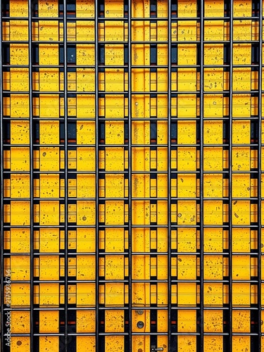 Yellow geometric blocks behind black grid pattern