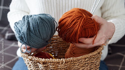 Obraz na płótnie Woman choosing colorful yarn skeins from a basket for a handmade knitting projec