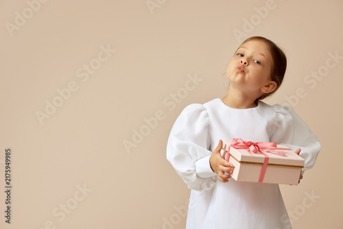 Obraz na plátně Little girl pouting holding pink gift box