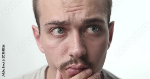 Extreme Close-up of Pensive Young Man Touching Chin and Thinking on White Background