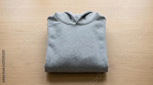 Folded gray hoodie sweatshirt on light wooden table surface