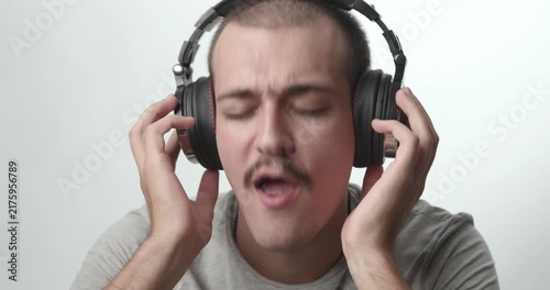 Close-up of Young Man Wearing Headphones Singing and Enjoying Music on White Background