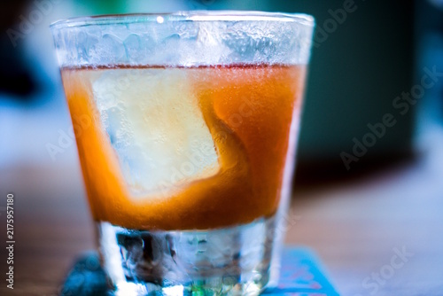 Bild auf Leinwand Close-up of orange cocktail with large rectangular ice cube, in old-fashioned gl