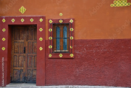 Foto Colonial house facade with an antique wooden door and window on a Venetian red stucco wall in San Miguel de Allende, Guanajuato Mexico
