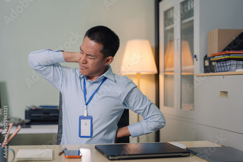 Quadro su tela Male businessman is doing a stretchy posture due to sitting in the office for too long, office syndrome concept