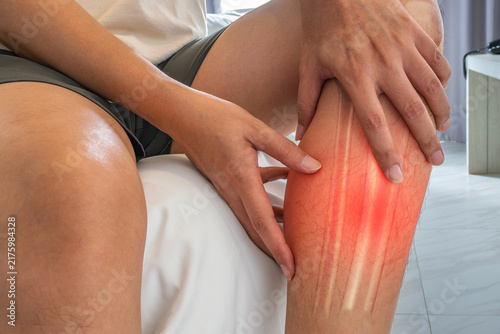 Fotografía Shin pain showing a man holding his lower leg due to discomfort for specialized medical treatment and orthopedic care illustration