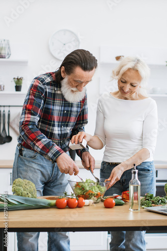 Foto An elderly couple happily prepares a fresh salad together in a bright, modern ki