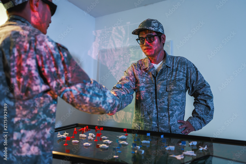 Obraz premium Two uniformed soldiers review a digital tactical map table, planning a military operation in a modern command room.