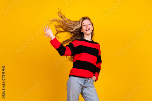 Charming young woman in a striped sweater posing cheerfully against a vibrant yellow background  highlighting cute and trendy fashion