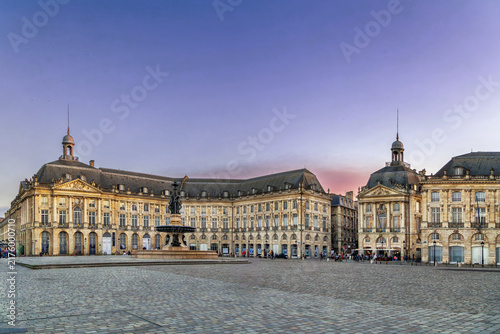 Bild auf Leinwand Asymmetric view of Place de la Bourse palace facade under a colorful sunset sky in Bordeaux, France