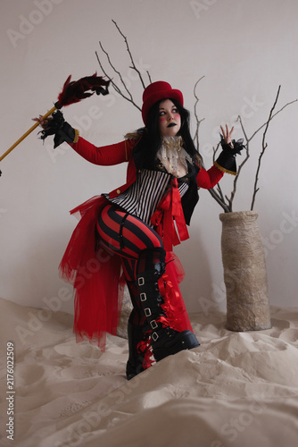 Фотография Ringmaster in red costume raising arms in triumphant gesture beside bare branche