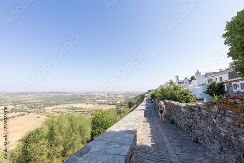 Canvastavla View of a winding path along a stone wall with a woman walking toward the horizo