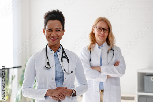 Portrait of two diverse female physicians standing confidently together, representing women, diversity and inclusion in modern healthcare