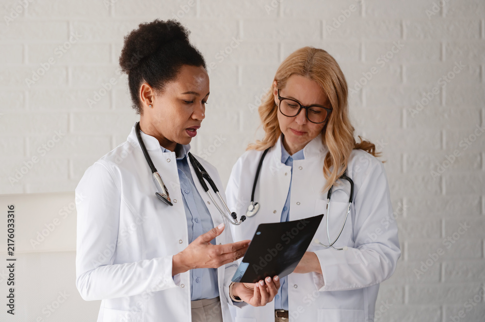 Fototapeta premium Female doctors sharing medical expertise and discussing a patient case while examining diagnostic imaging together