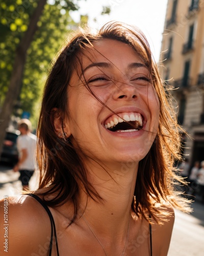 Joyful young woman laughing heartily outdoors in a sunny city street