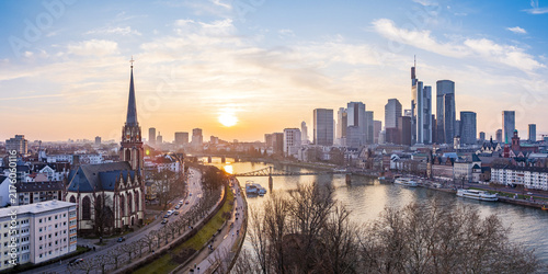 Aerial view of Dreikonigskirche situated along the Main river with the Frankfurt skyline in the background during a golden sunset in Frankfurt am Main, Hessen, Germany.