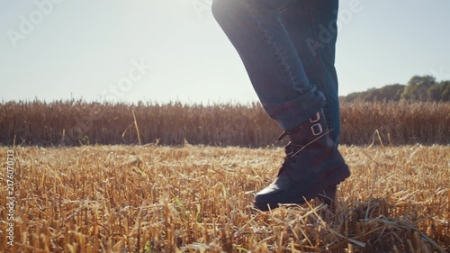Farmer wearing boots walks along cut ripe wheat field stubble