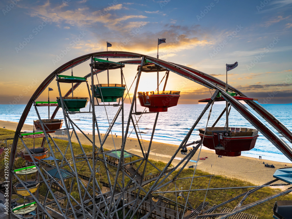 Aerial view of the Carolina Beach Boardwalk Amusement Park ferris wheel with colorful gondolas overlooking the beach and ocean at sunset, Carolina Beach, North Carolina, United States.